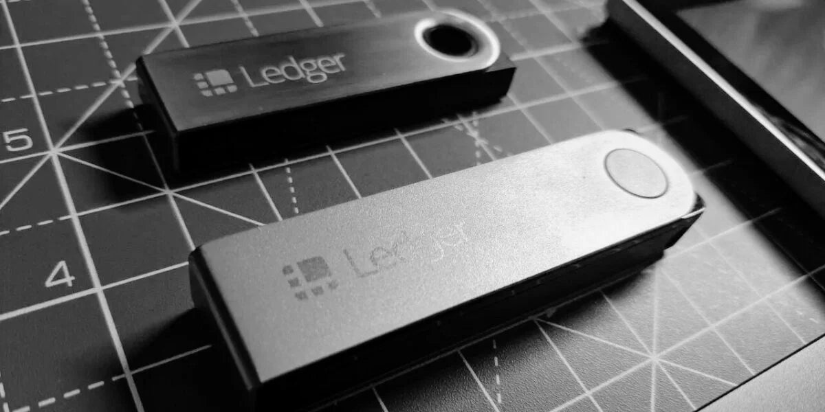 Two Ledger Nano hardware wallets on a cutting mat, photographed in black and white
